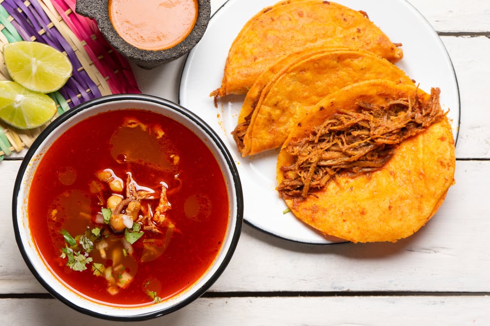 Mexican birria consomme and beef tacos on white background